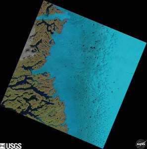 Supraglacial lakes on the Greenland ice sheet can be seen as dark blue specks in the centre and to the right of this satellite image.  Credit: USGS/NASA Landsat 